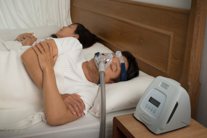man sleeping in bed with CPAP machine
